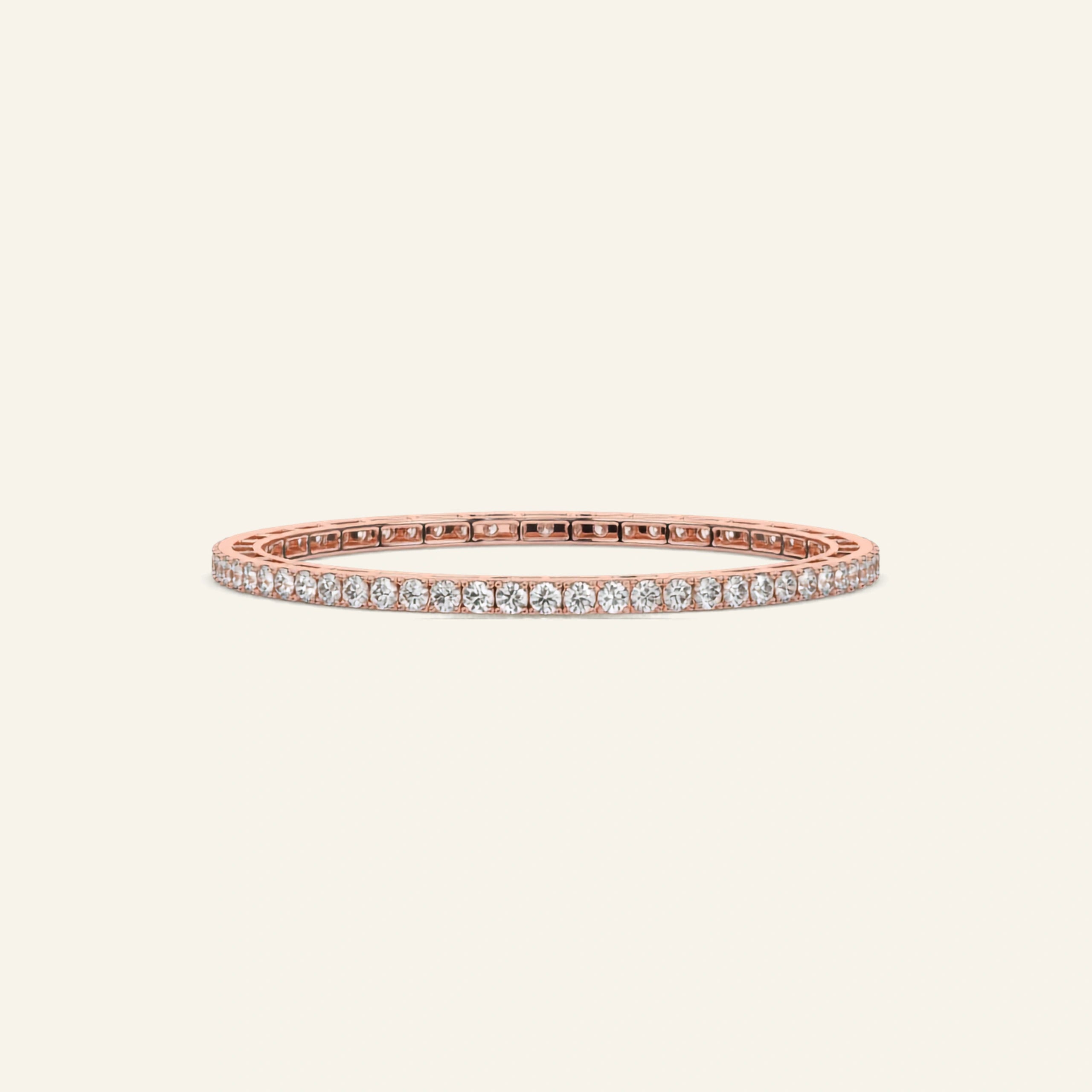 A rose gold tennis bangle bracelet with a row of clear round-cut gemstones, displayed against a solid off-white background.