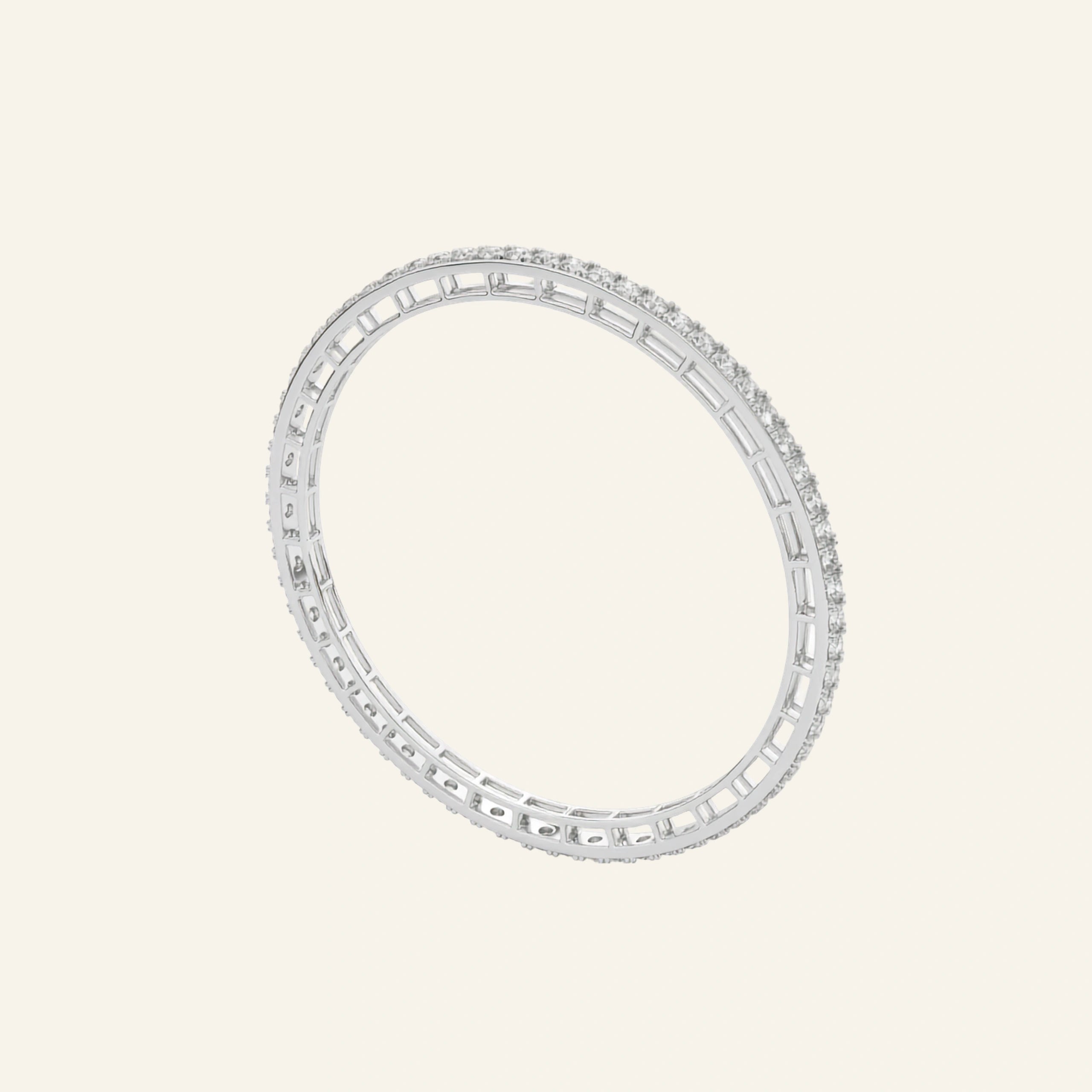 A White Gold eternity bangle bracelet featuring baguette and round-cut clear stones, shown on a solid cream-colored background.